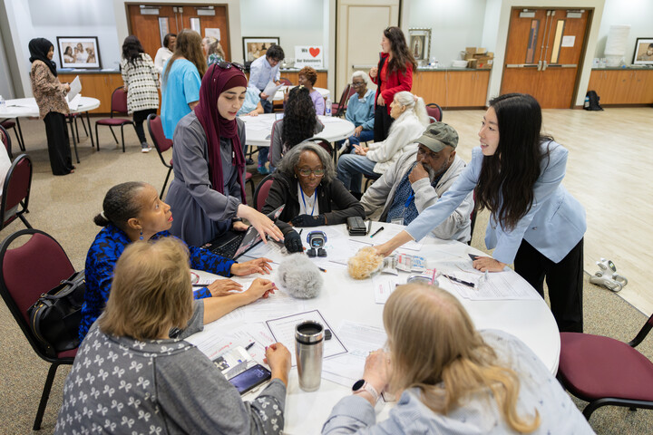 Workshop participants and facilitators explore small companion robots together at a table.