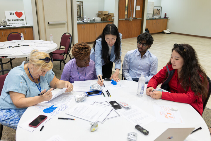 A small group works with clay and worksheets while a facilitator joins the conversation.