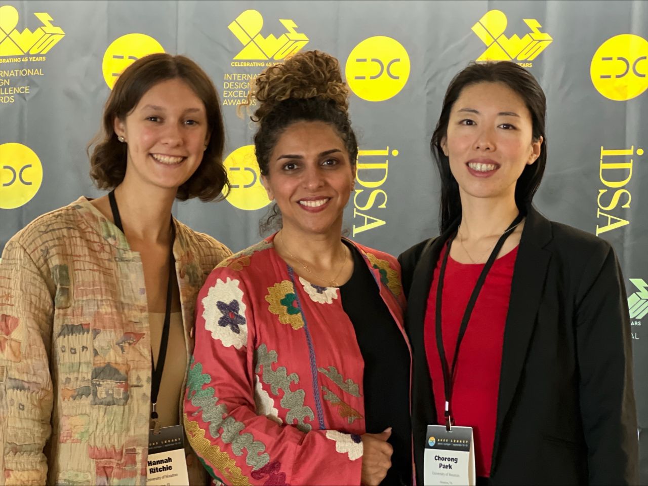 Three attendees pose in front of an IDSA event backdrop.