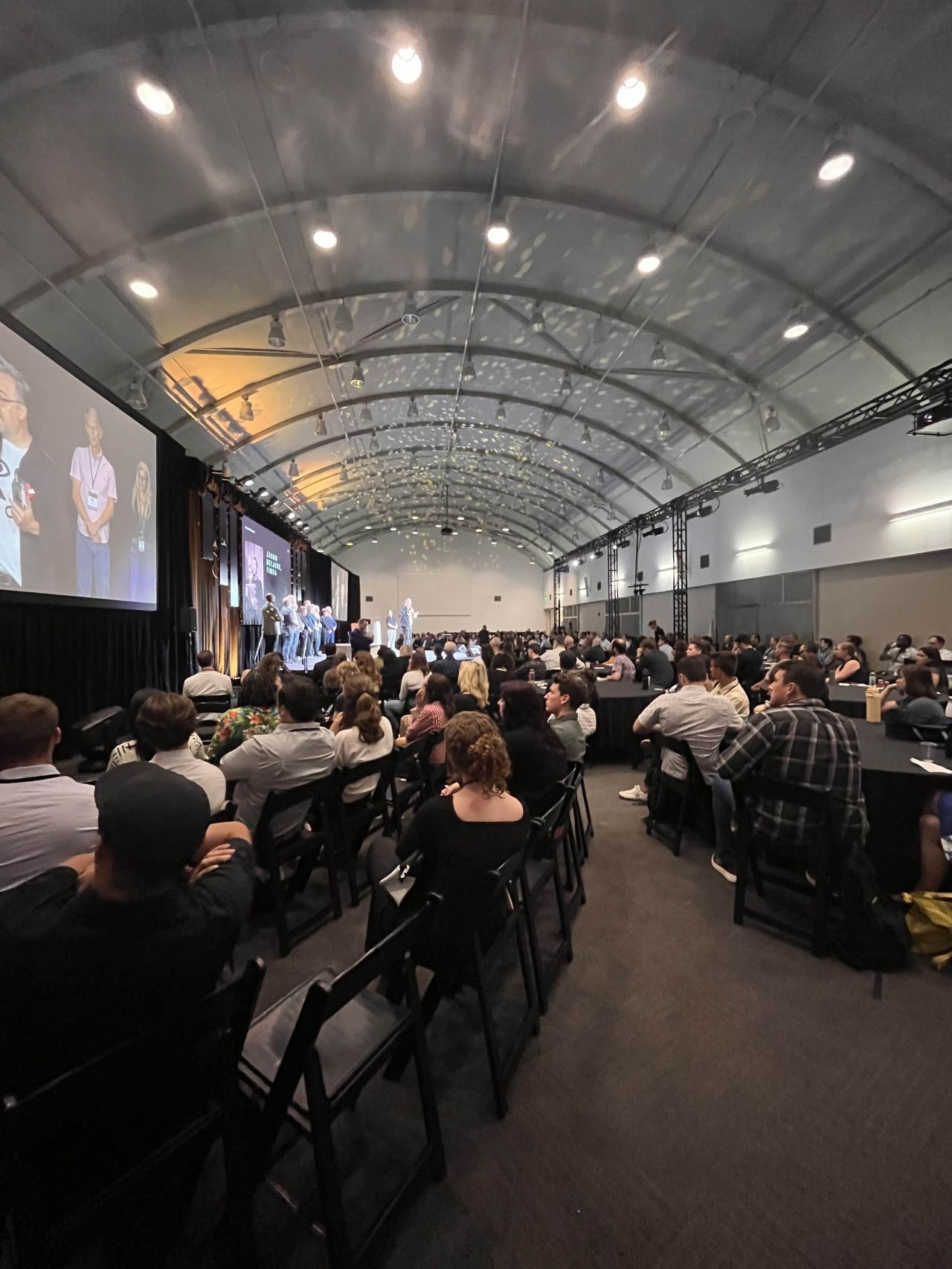 An audience watches a stage presentation in a large hall.
