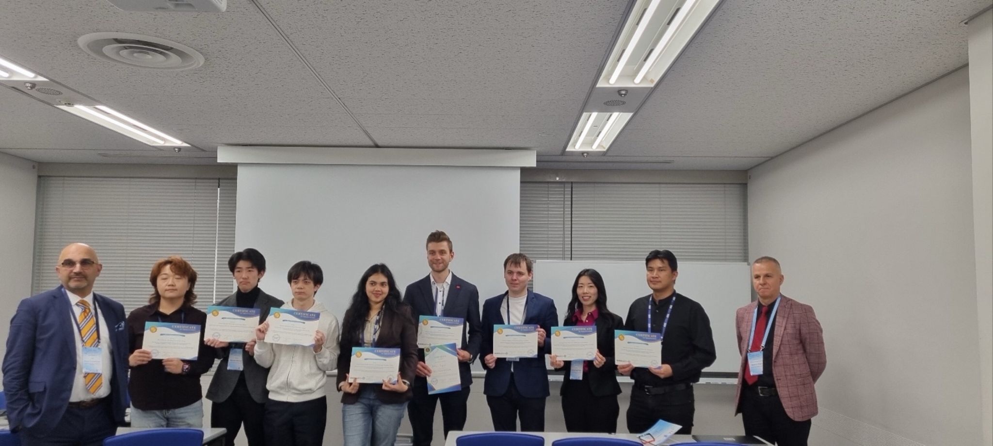 Conference participants stand together holding certificates.