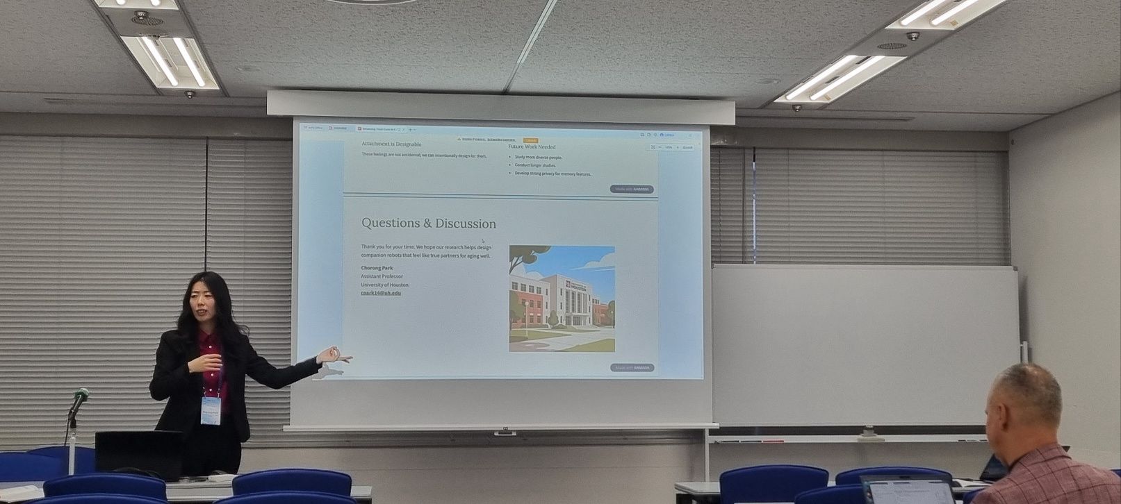 A presenter stands beside a projected questions-and-discussion slide.