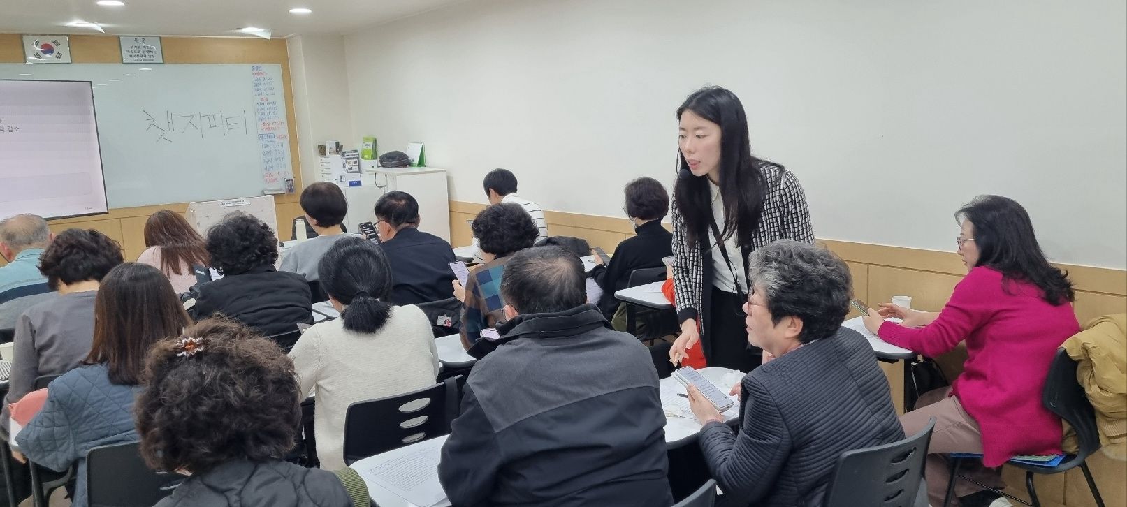 An instructor speaks with a participant between rows of classroom seats.