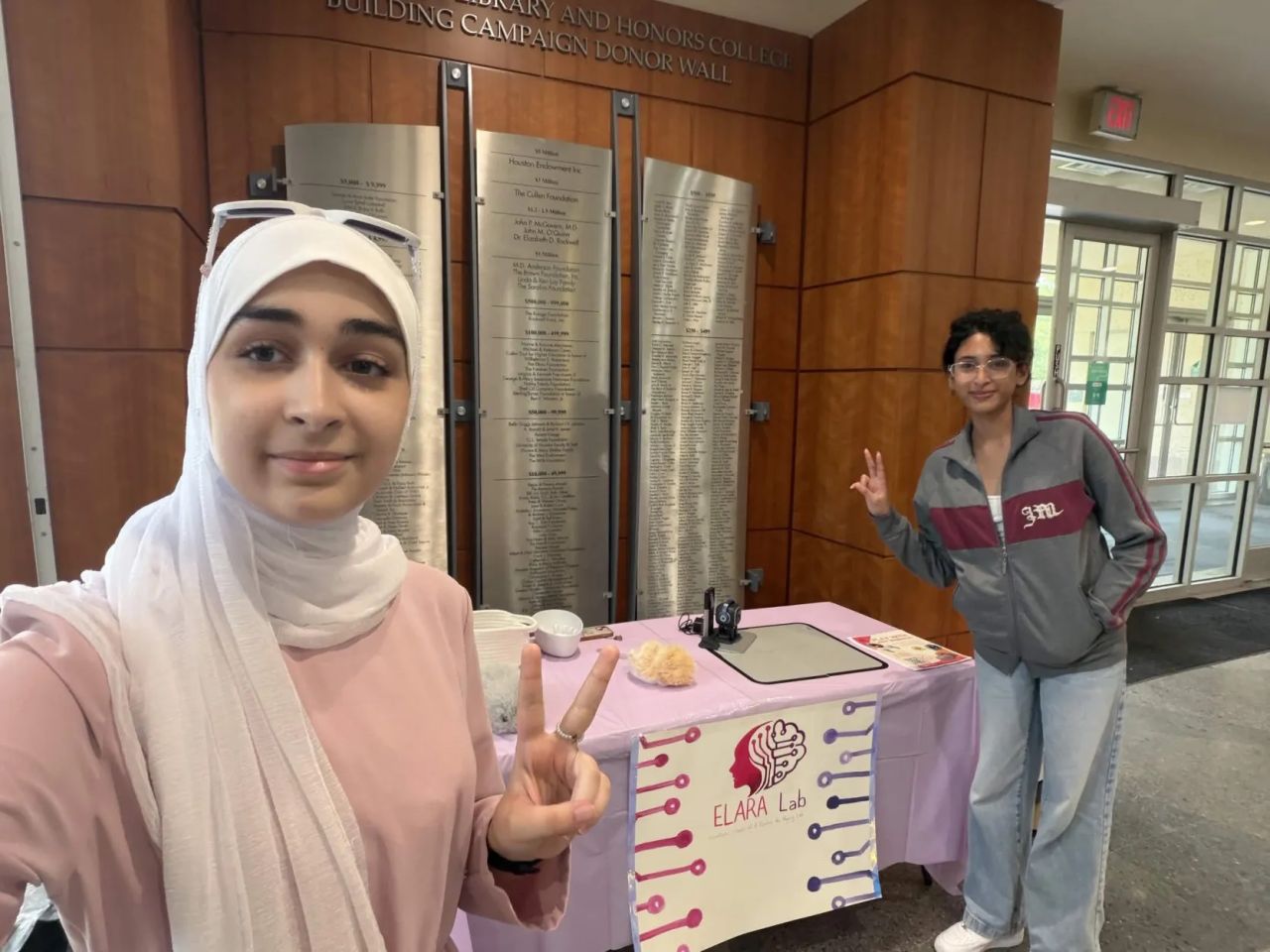 Two participants pose beside the ELARA Lab recruitment table.