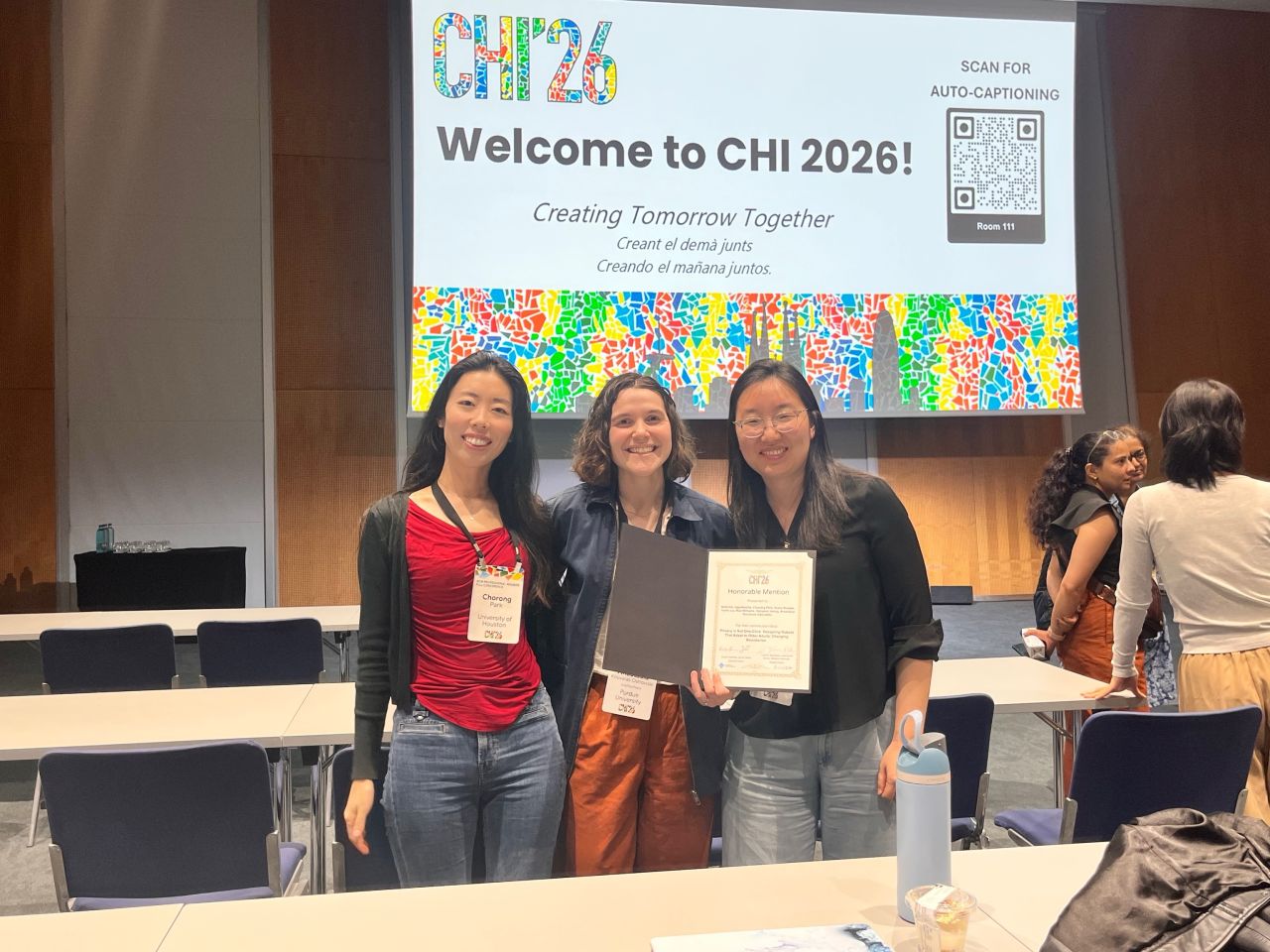 Three conference attendees pose with a certificate in front of a CHI 2026 welcome screen.
