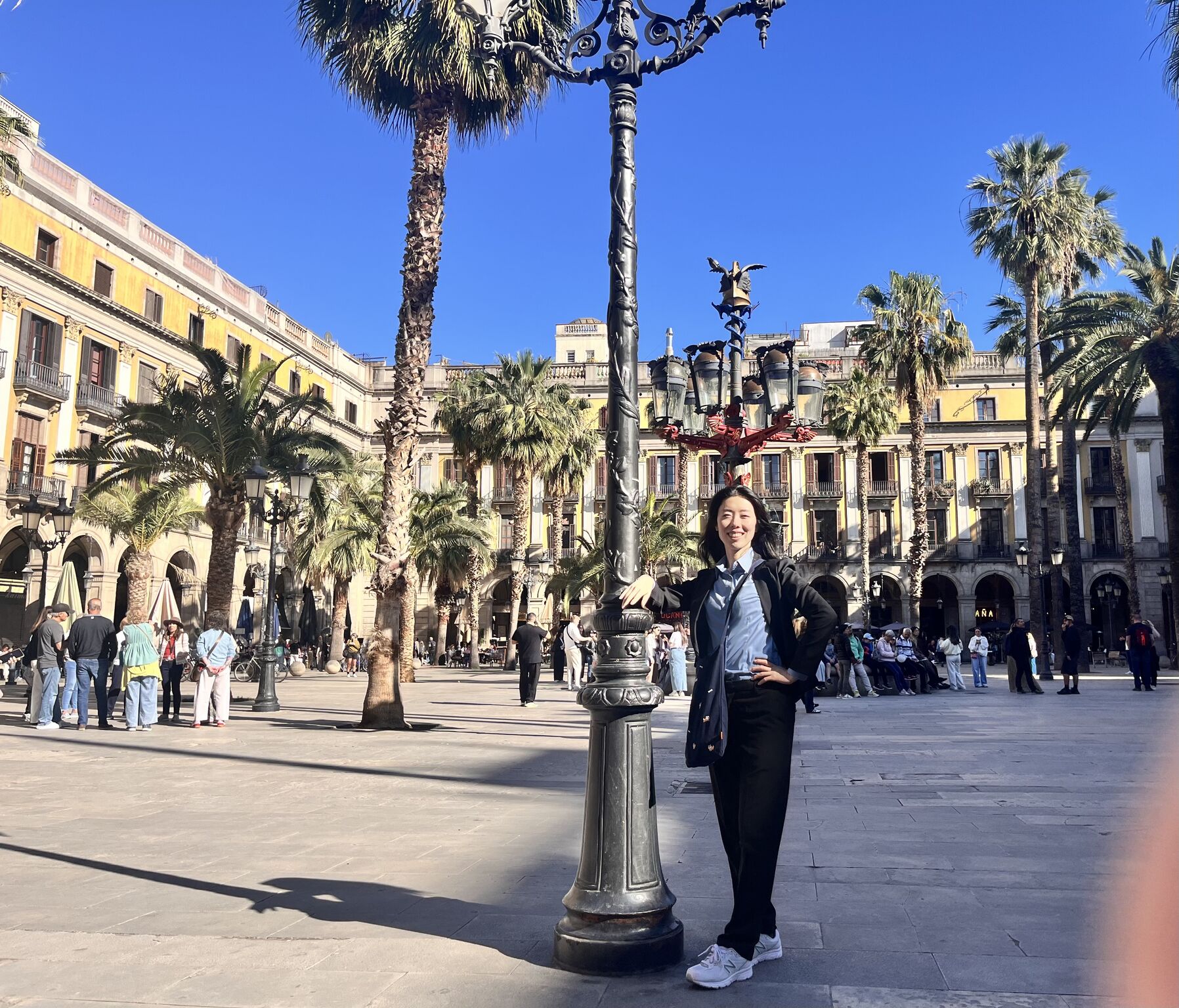 An attendee stands in a palm-lined city square.