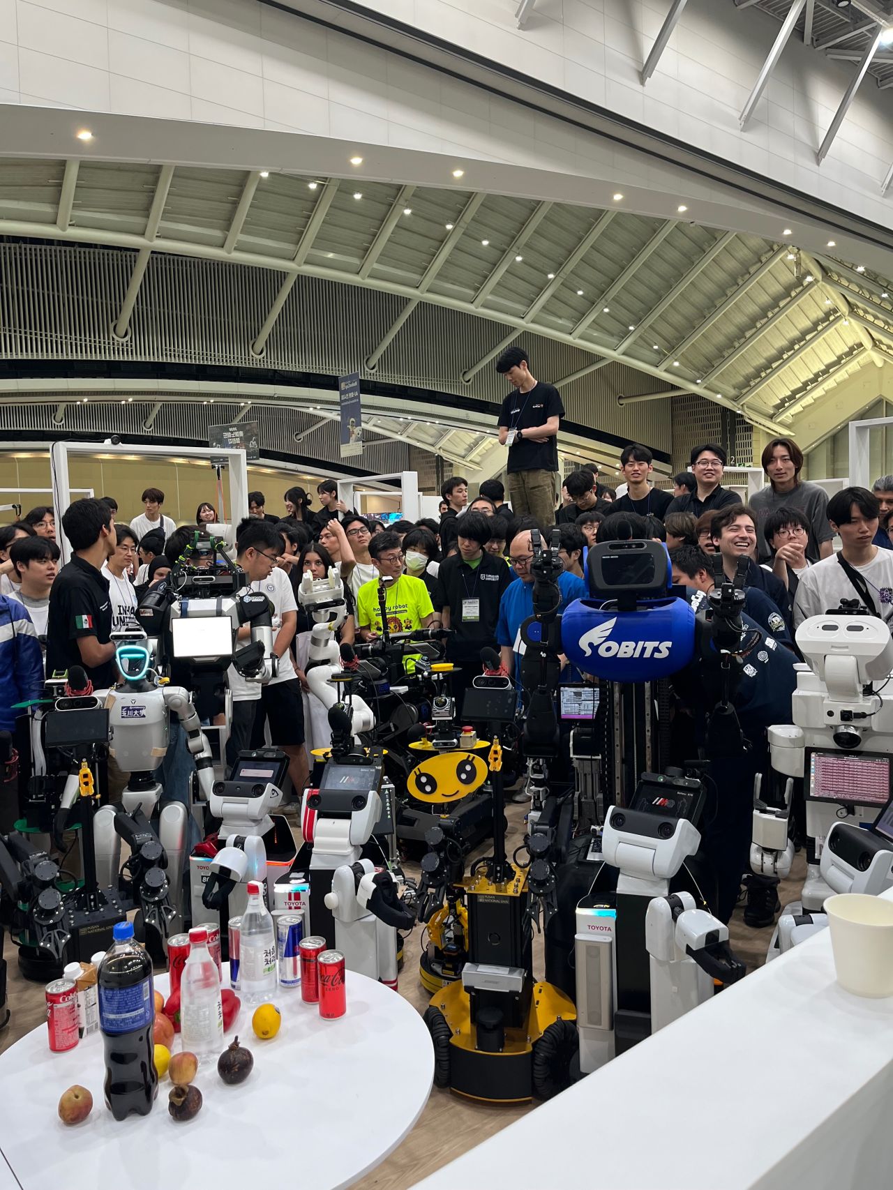 A large group poses behind a lineup of service robots.
