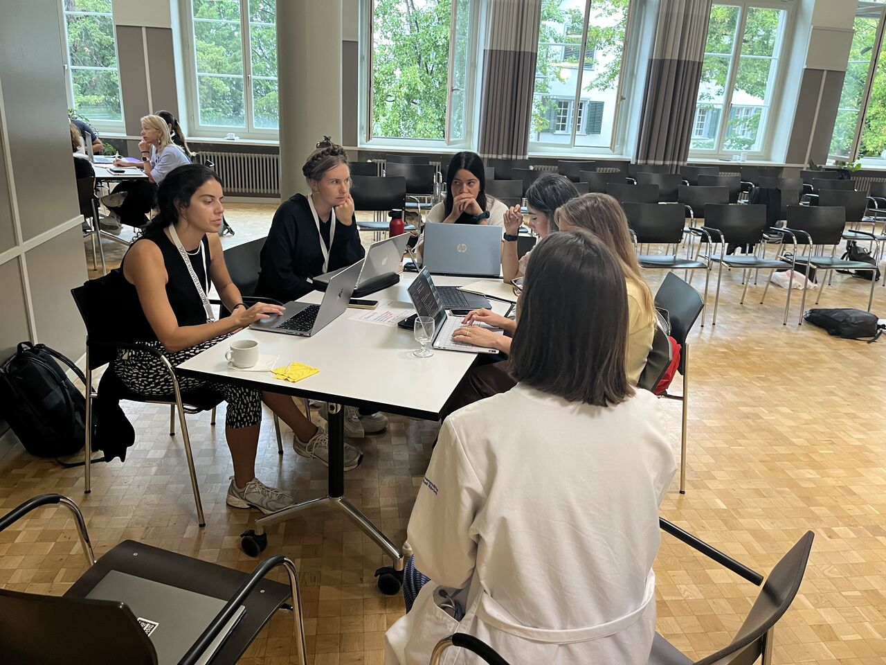 Participants work together at a table with open laptops.