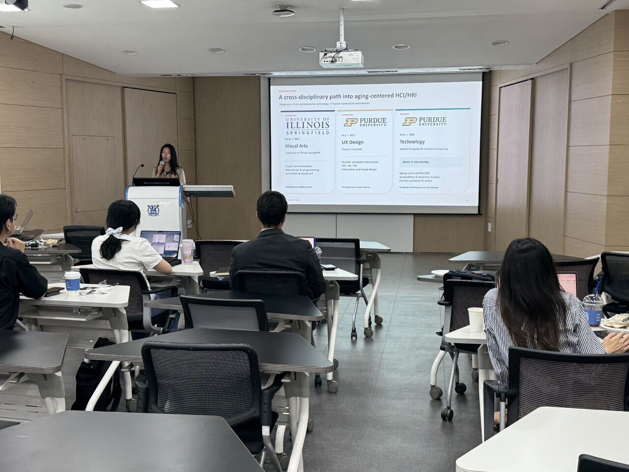 Participants face a projected slide comparing research approaches.