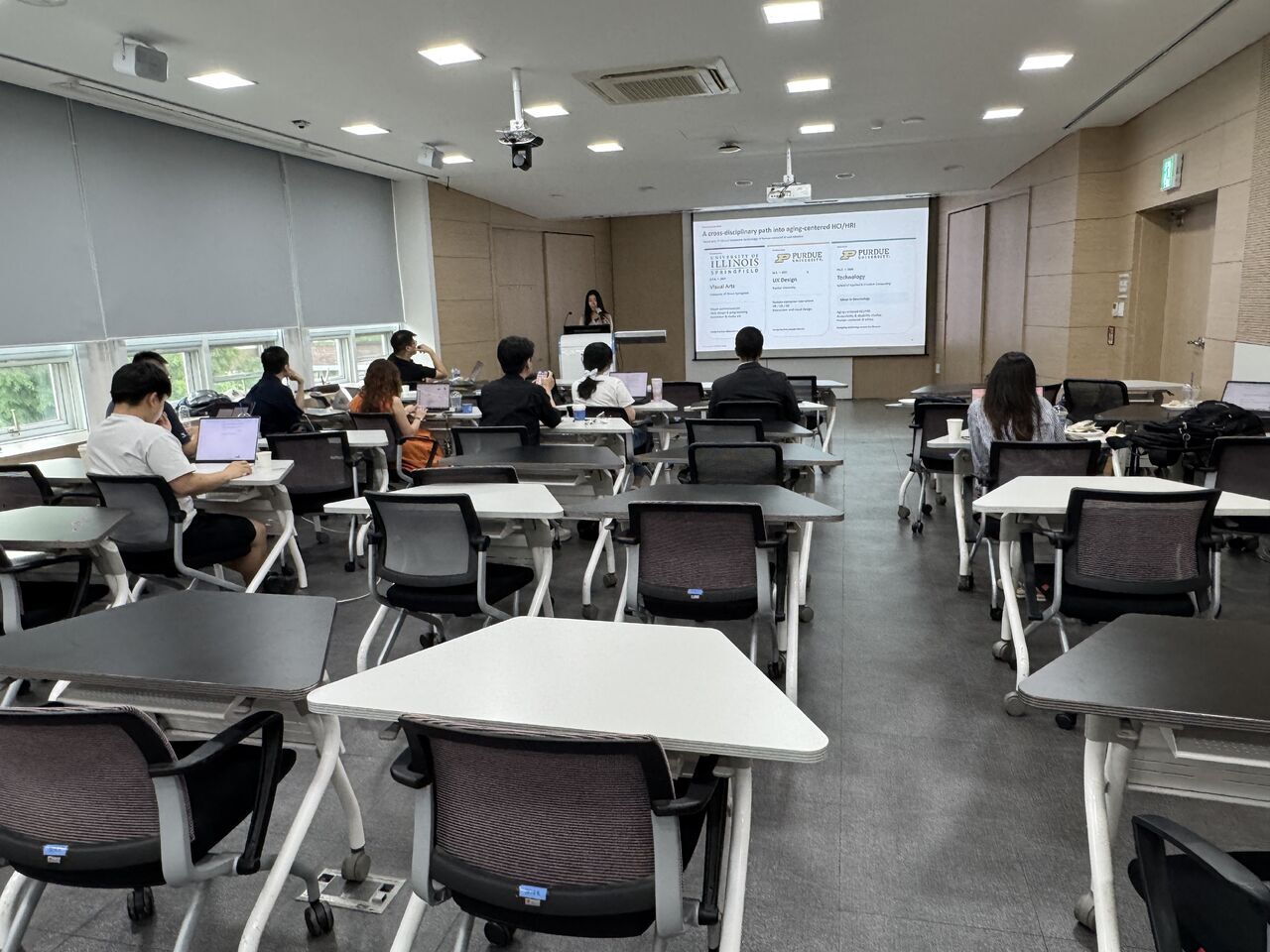 A wide rear view of a classroom presentation and audience.