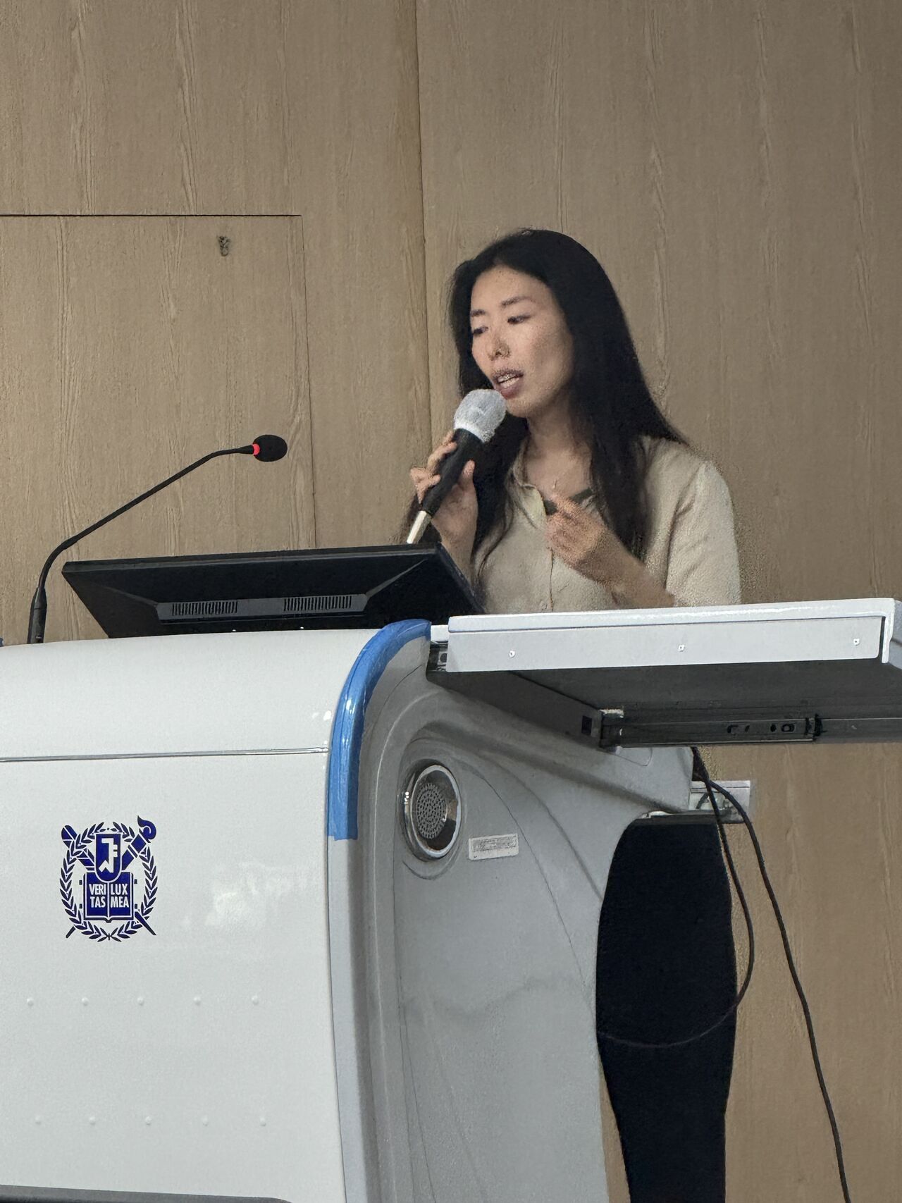 A closer view of a presenter speaking into a handheld microphone.