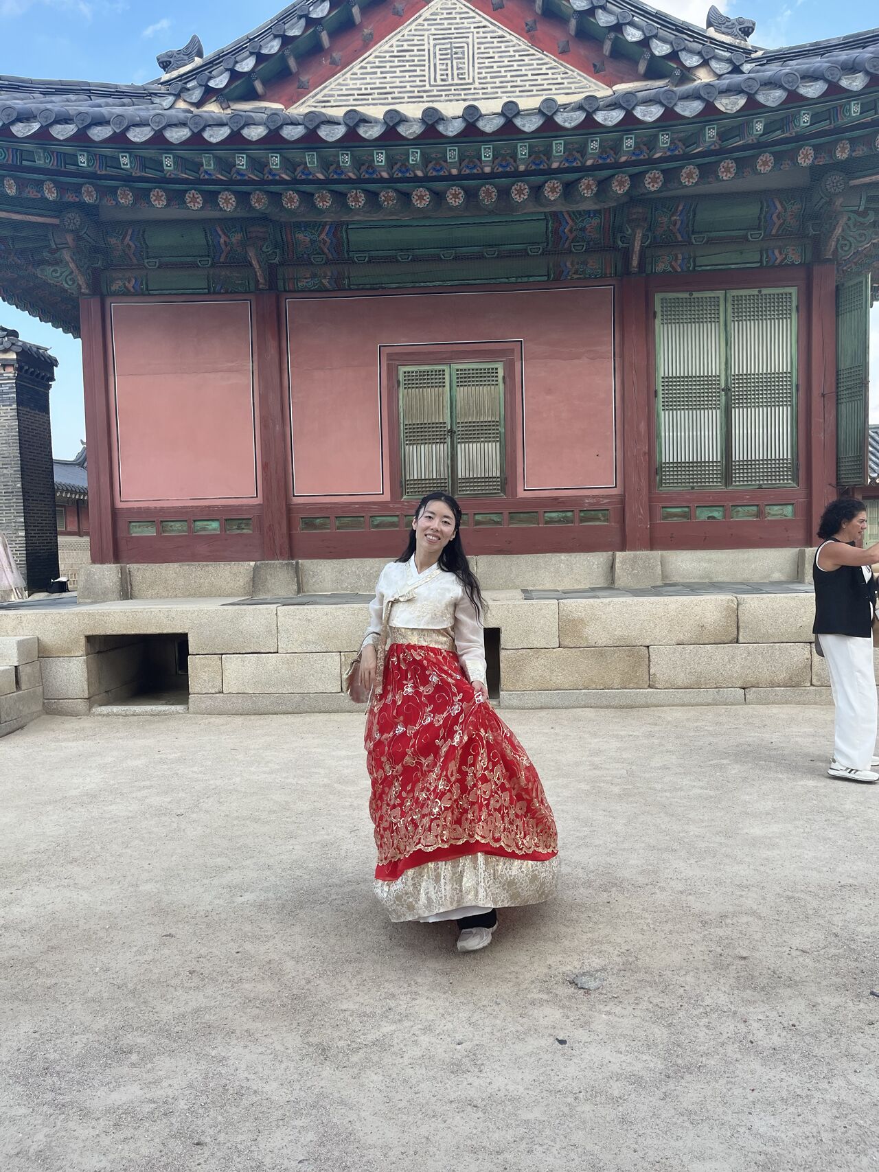 A visitor poses in traditional clothing in front of a historic building.