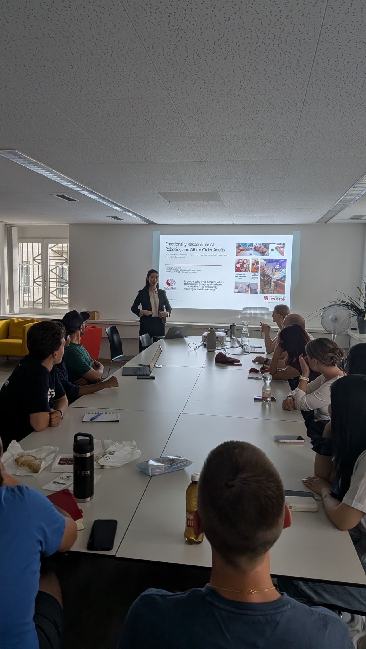 A presenter addresses colleagues seated around a meeting table.