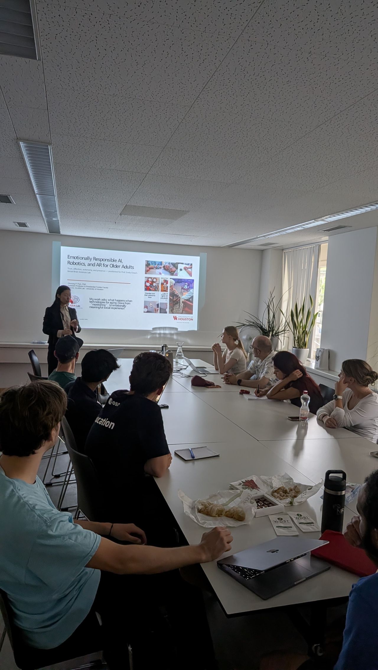 A view along a meeting table toward a presenter and projected images.