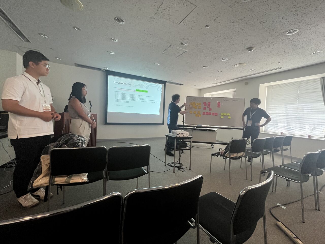 Workshop participants discuss ideas beside a board covered with sticky notes.