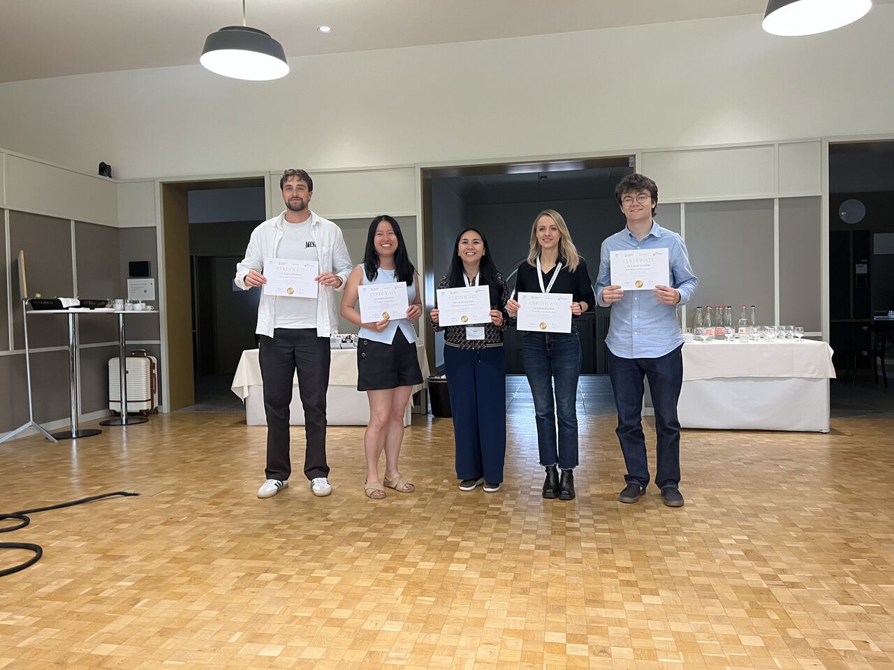 Five participants hold certificates for a group photograph.