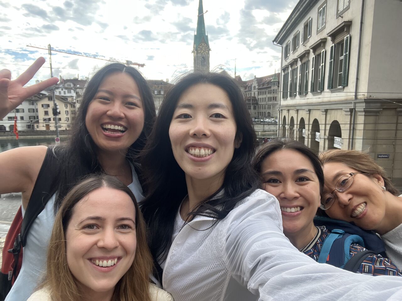 A group takes an outdoor photograph with city buildings behind them.