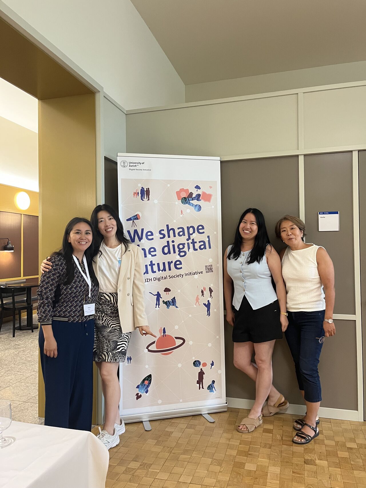 Three participants pose beside a digital health event banner.