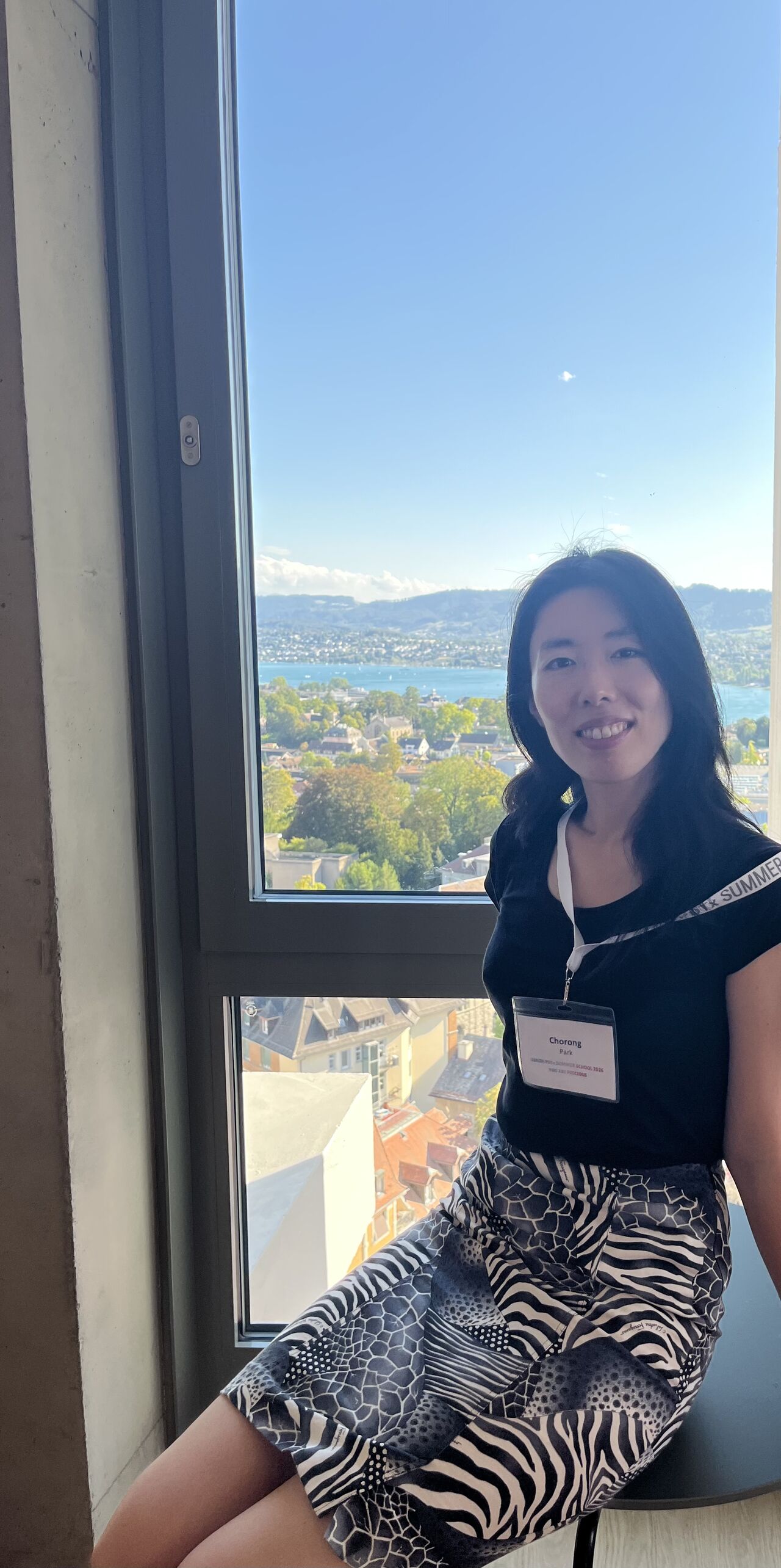 A participant poses beside a window overlooking the city.
