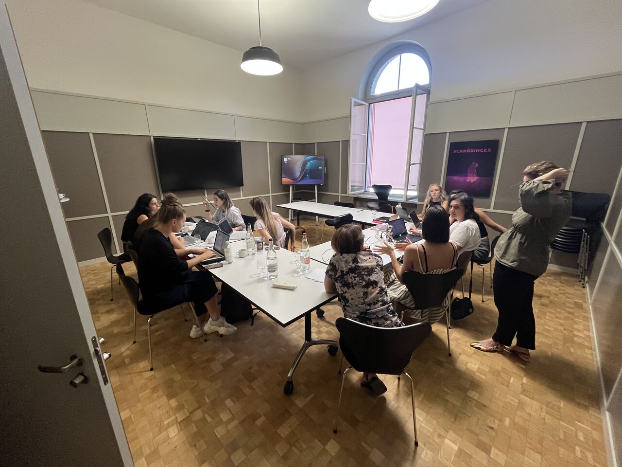 A group works together around a table in a workshop room.