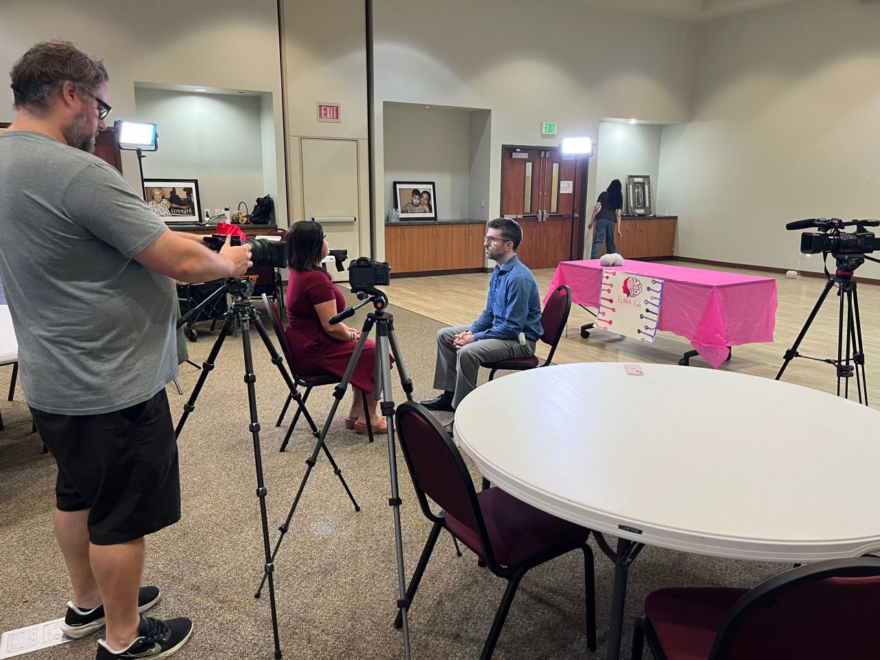 A camera operator films an interview with a seated community participant.