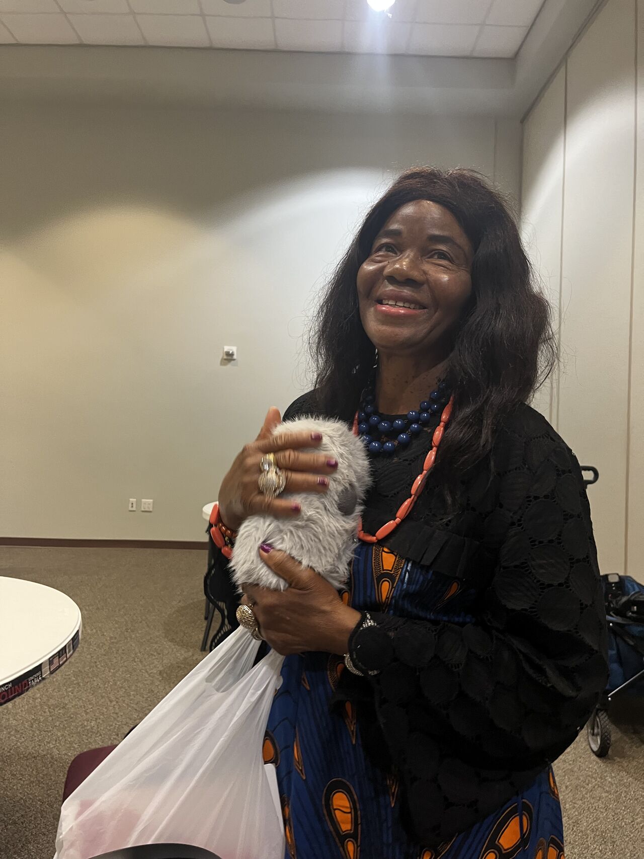 A community participant smiles while holding a small furry companion robot.